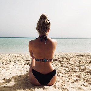 Frau sitzt alleine am Strand